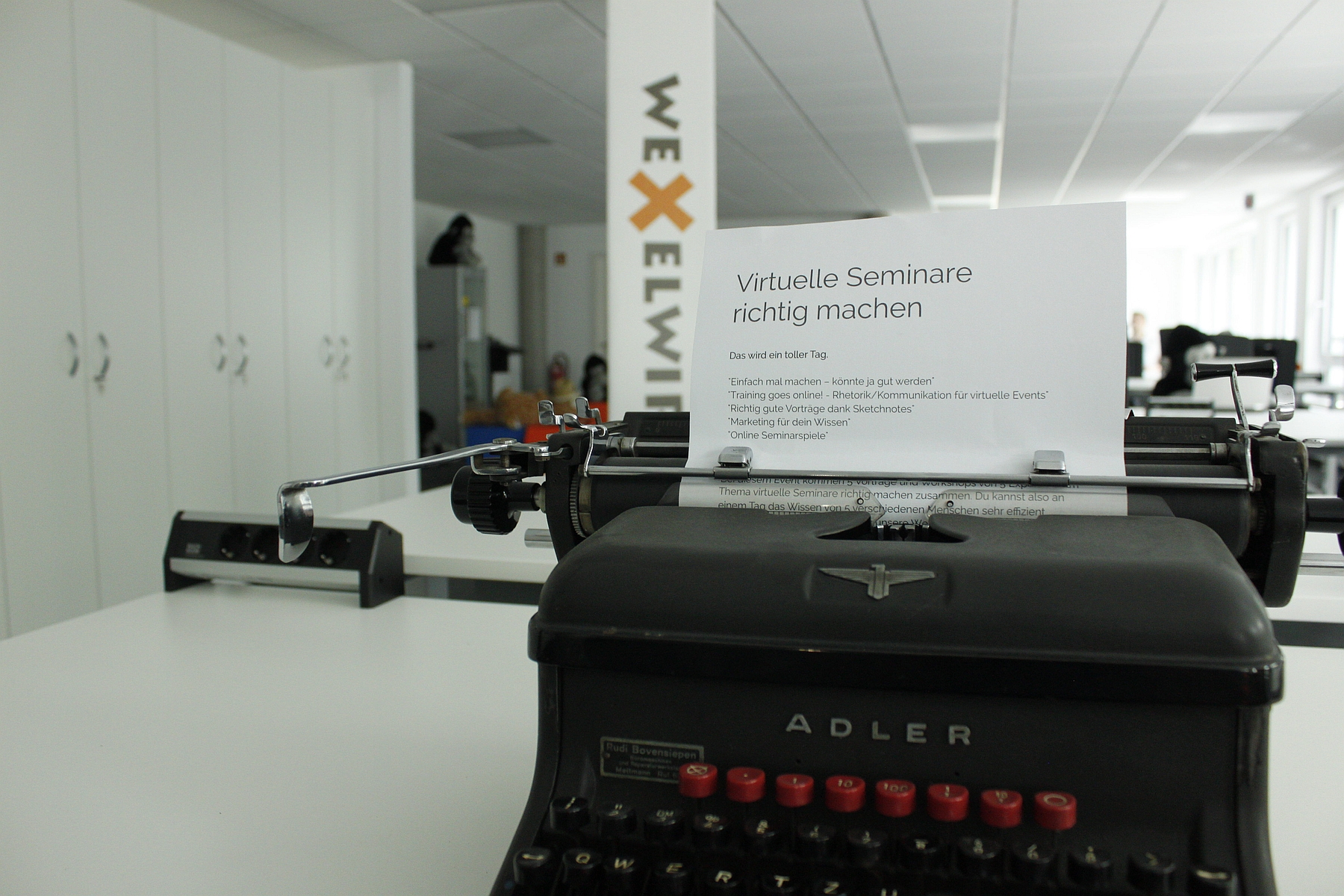Schreibmaschine mit einem Blatt auf dem der Titel der Veranstaltung steht